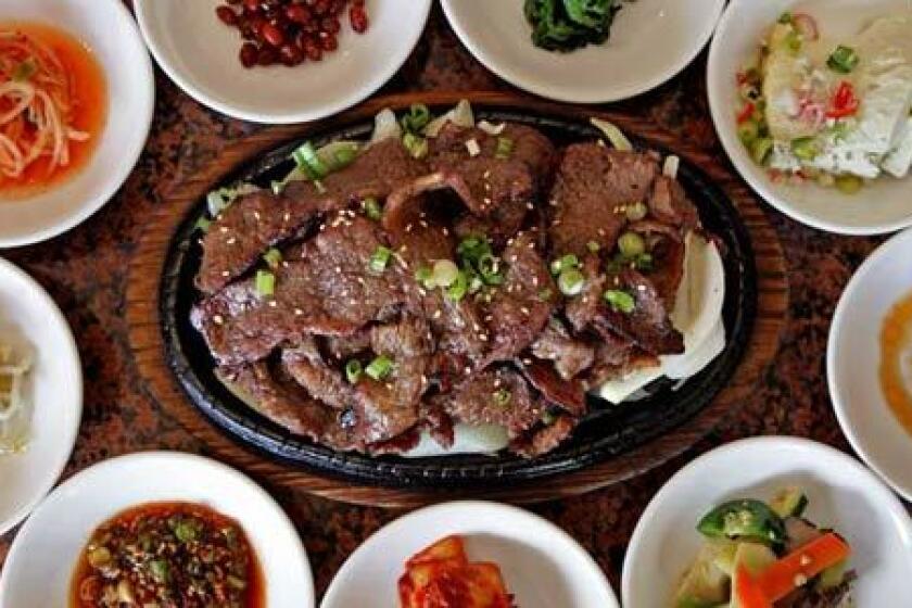 Marinated sliced beef with assorted small plates at Seongbukdong Korean restaurant.