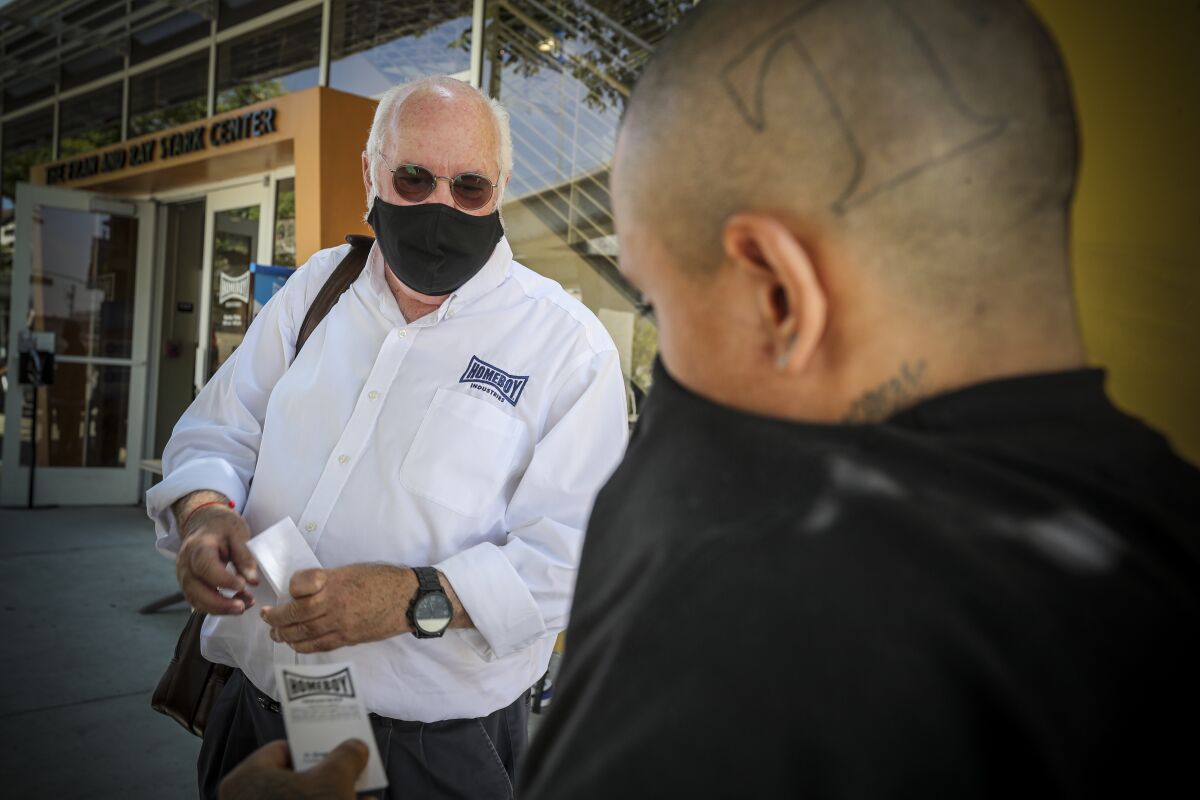 Father Greg Boyle, left, of Homeboy Industries meets a visitor who wasn't wearing a mask.