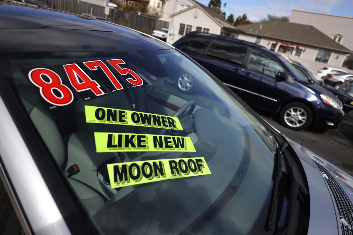 Closeup of a car windshield with stickers that read 'one owner,' 'like new' and 'moon roof.'