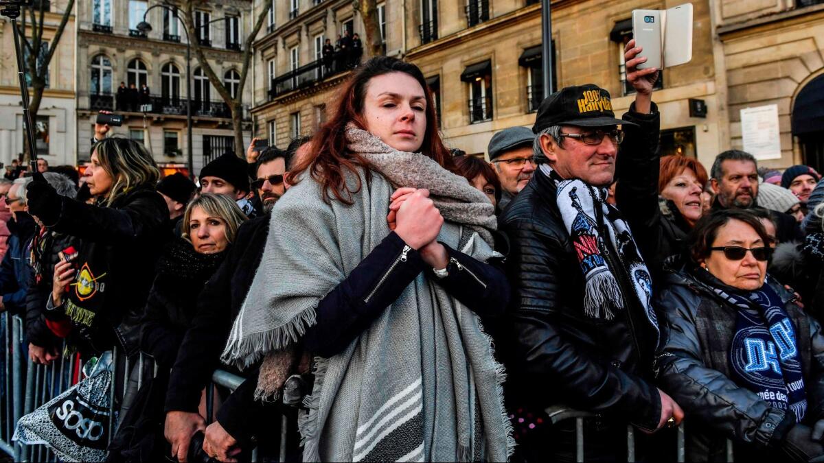 People gather outside the Catholic Church of La Madeleine during the funeral services Saturday for French singer Johnny Hallyday.