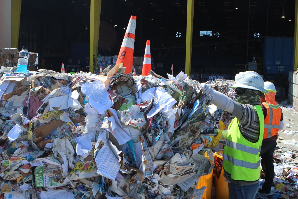 Workers perform a newly added step in the sorting of recyclables at the Allan Company's Miramar facility