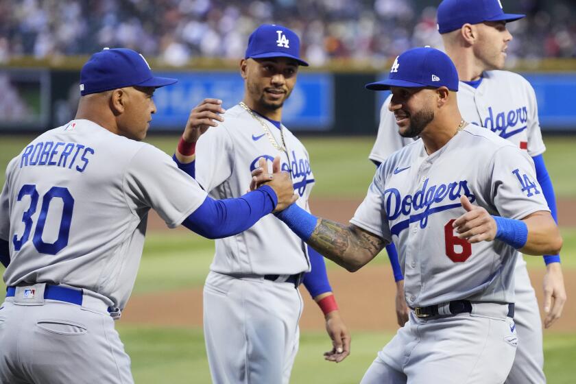 Los Angeles Dodgers manager Dave Roberts (30) shakes hands with Dodgers' David Peralta.