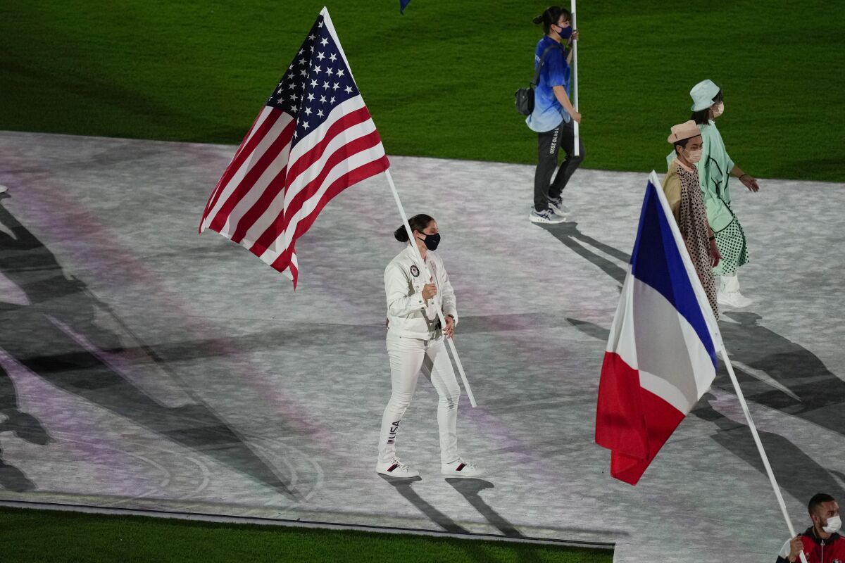 Kara Winger, of the United States of America, and Steven Da Costa, of France, carry their country's flags during the closing ceremony in the Olympic Stadium at the 2020 Summer Olympics, Sunday, Aug. 8, 2021, in Tokyo, Japan. (AP Photo/Vincent Thian)