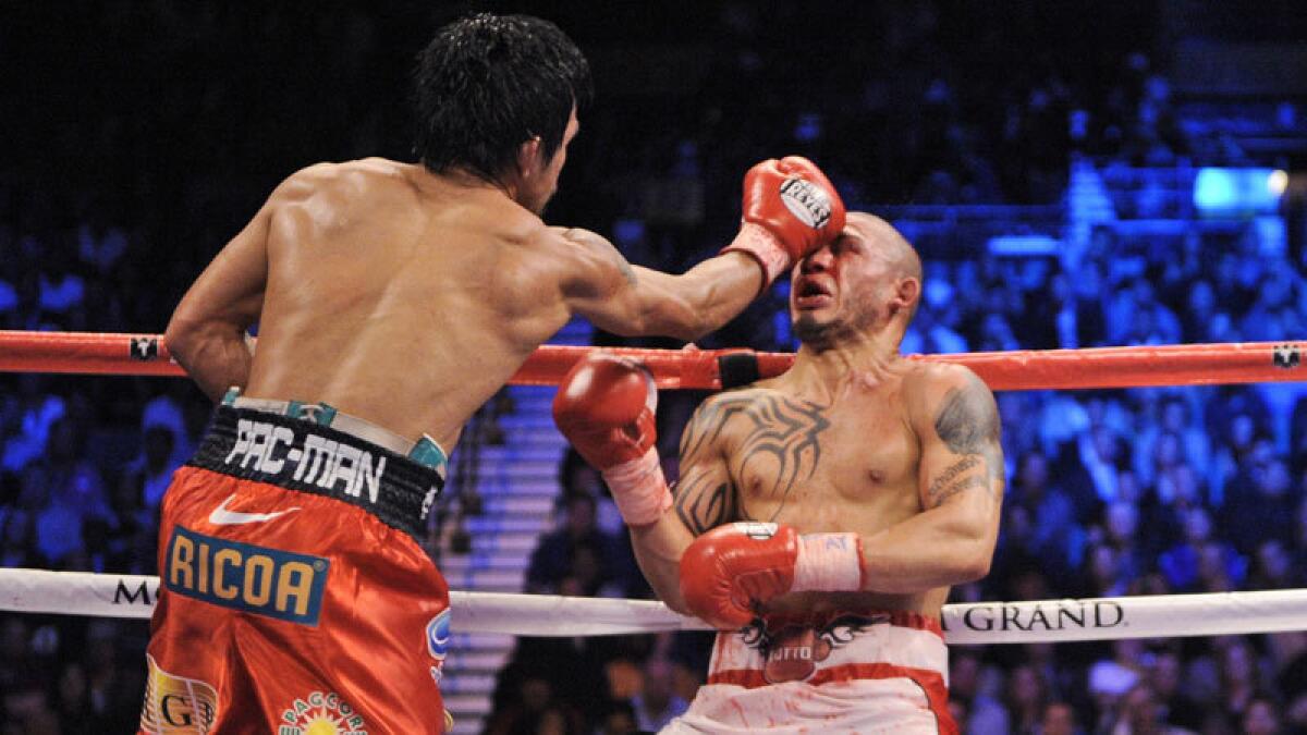 Manny Pacquiao hammers Miguel Cotto against the ropes during their fight.
