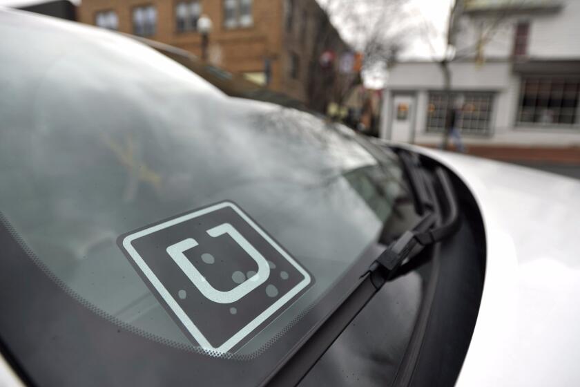 An Uber decal is displayed in the their window of a car.