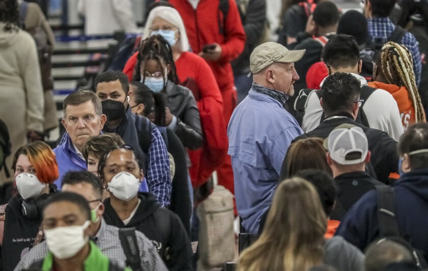 Crowds of the masked and the unmasked went through the security line at Hartsfield-Jackson International Airport on Tuesday, April 19, 2022 where the airport issued a statement Tuesday morning saying masks are now "optional for employees, passengers, and visitors" at the airport. "Although a mask mandate will no longer be enforced, employees, passengers, and visitors are reminded that masks continue to offer a level of protection against the COVID virus," the airport said. (John Spink/Atlanta Journal-Constitution via AP)