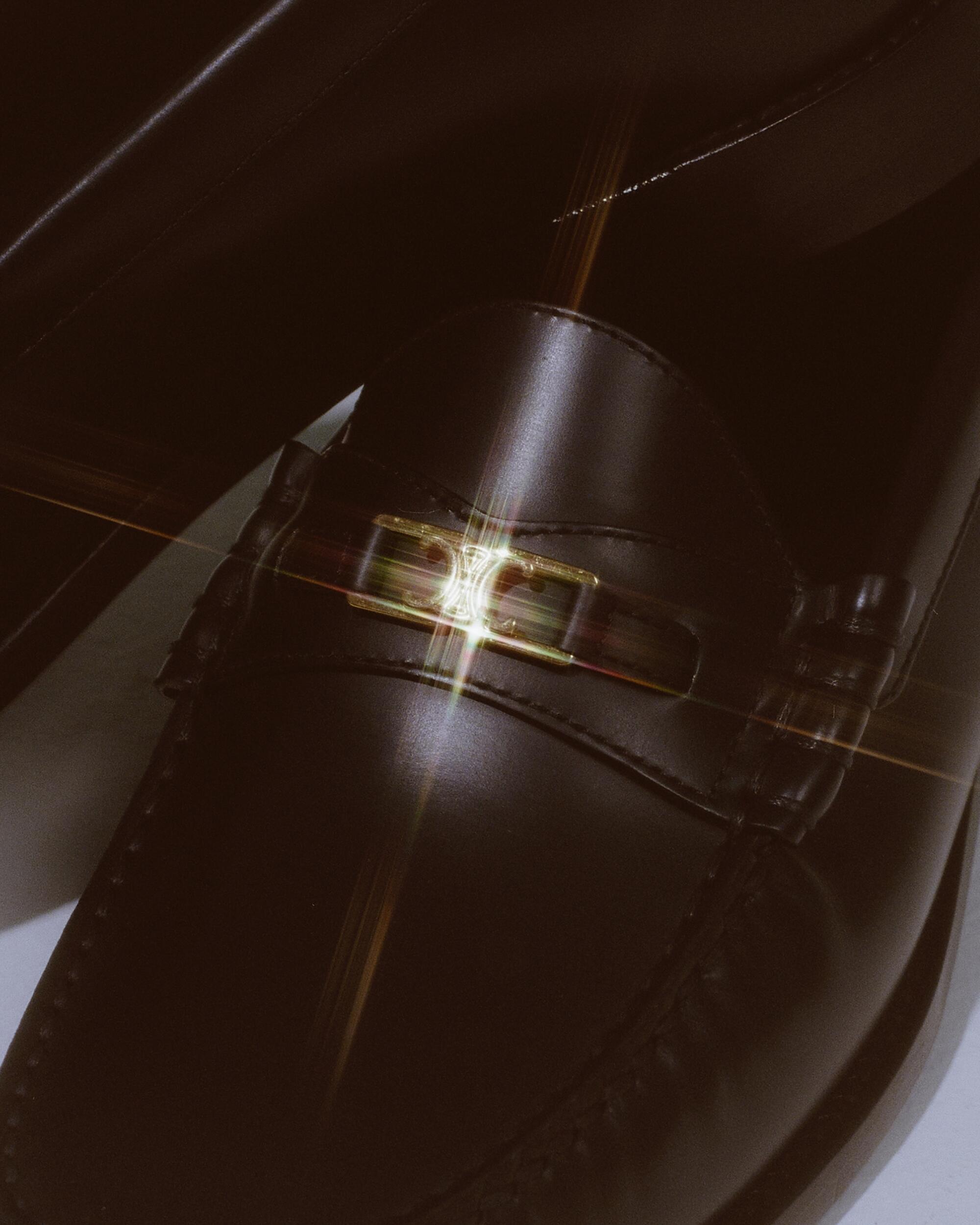 A closeup of a glistening Celine black house shoe