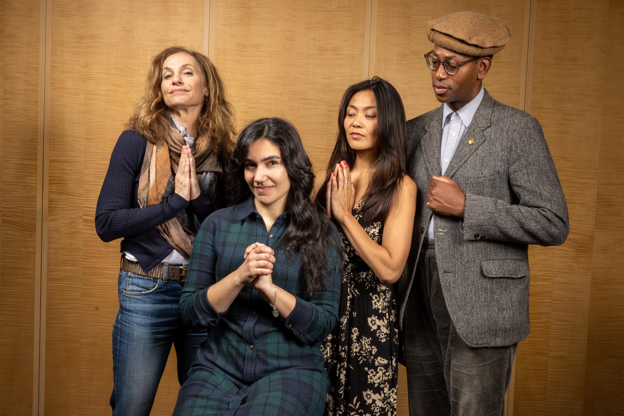 Four people in modern clothing smile and hold their hands in prayer