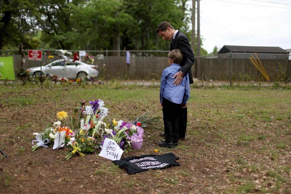 The Rev. Jeremy Rutledge and his son visit a memorial at the site where Walter Scott was killed by a North Charleston police officer in South Carolina. On Friday civil rights organizations called for a federal review of police shootings in the area.
