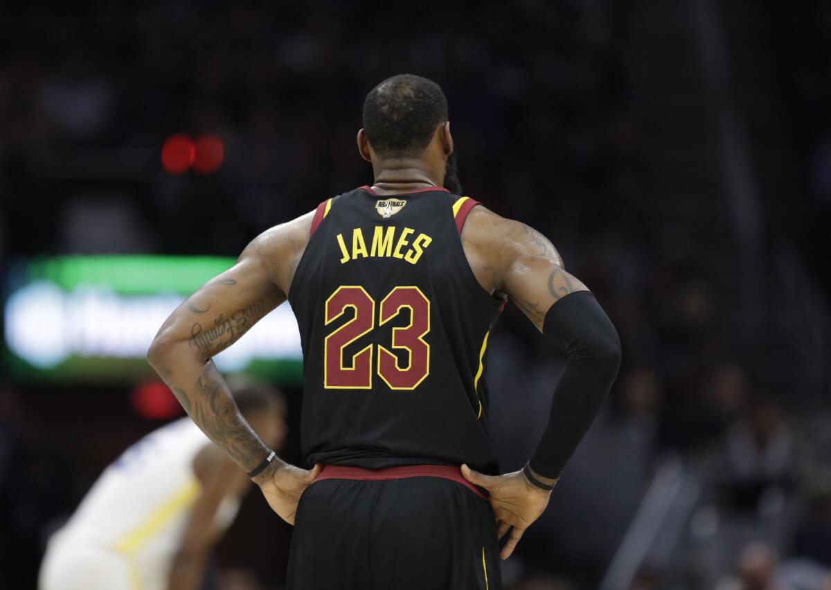 Cleveland Cavaliers' LeBron James stands on the court in the first half of Game 4 of basketball's NBA Finals against the Golden State Warriors in Cleveland. Cavaliers owner Dan Gilbert didn't trash James on his way out this time. He promised to retire his jersey.