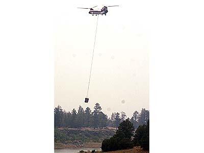 A water dropping helicoptor makes a run to battle the Rodeo/Chediski fire at the western edges of Show Low, Arizona