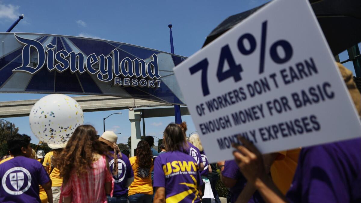 Protestors march at the Disneyland entrance in Anaheim on July 3. A measure on the Nov. 6 ballot will require hospitality businesses, including Disneyland, to pay workers a living wage.
