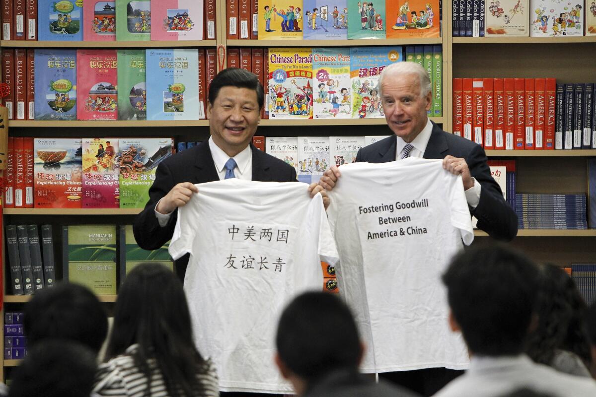 Xi Jinping and Joe Biden holding up T-shirts as students watch. Biden's says "Fostering goodwill between America & China."