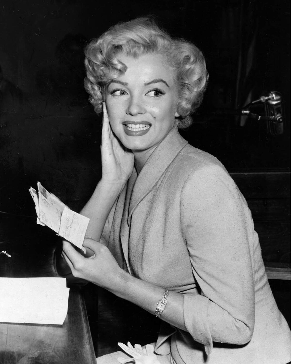 June 26, 1952: Marilyn Monroe in court examining letters introduced into evidence.