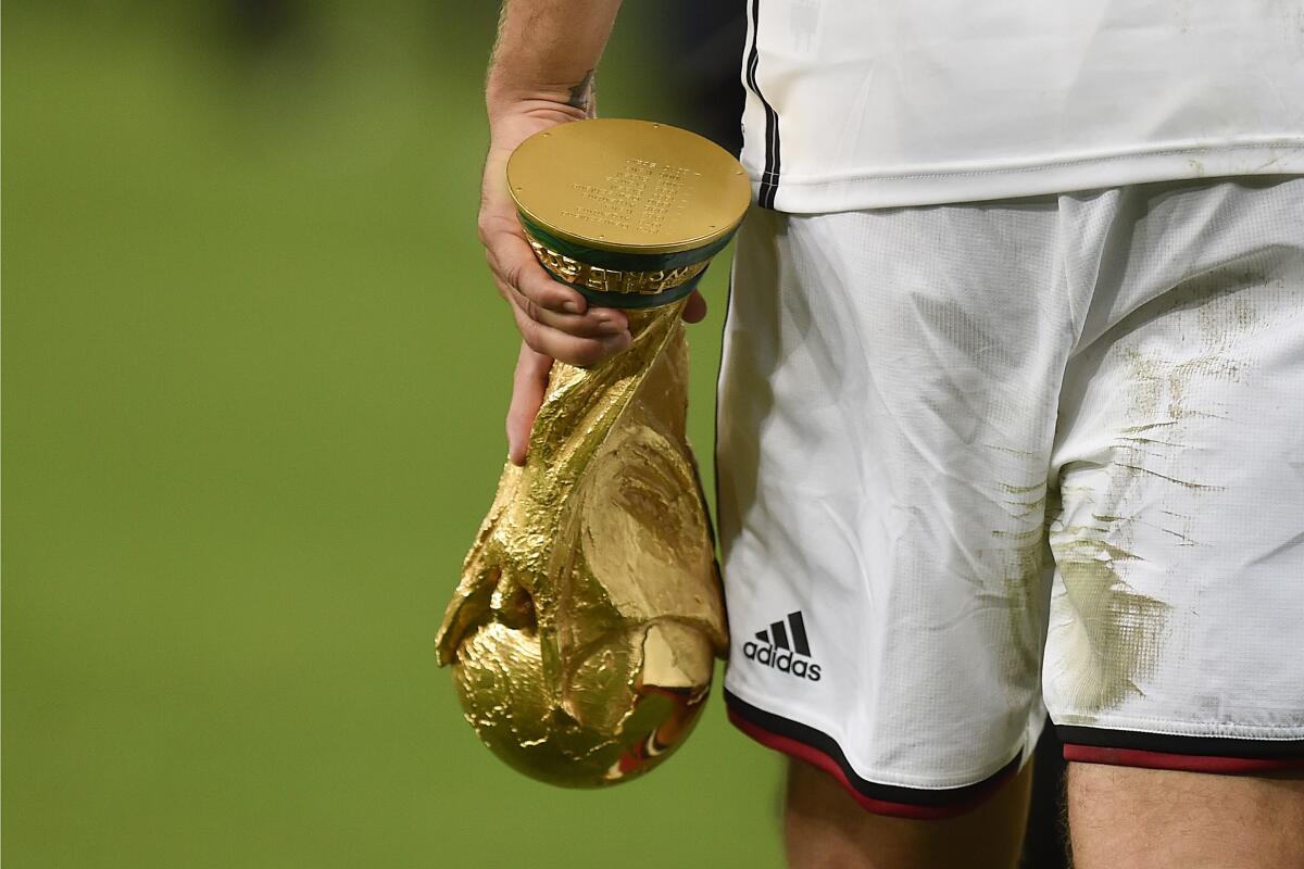 ARCHIVO - El delantero alemán Lukas Podolski se retira de la cancha con el trofeo de la Copa Mundial 