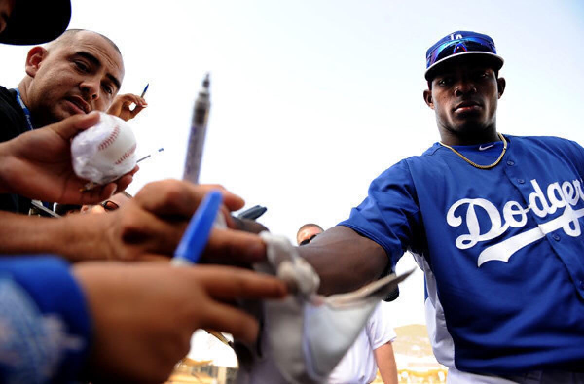 Dodgers right fielder Yasiel Puig gives away his batting glove to a fan before the game with the Braves on Friday at Dodger Stadium.