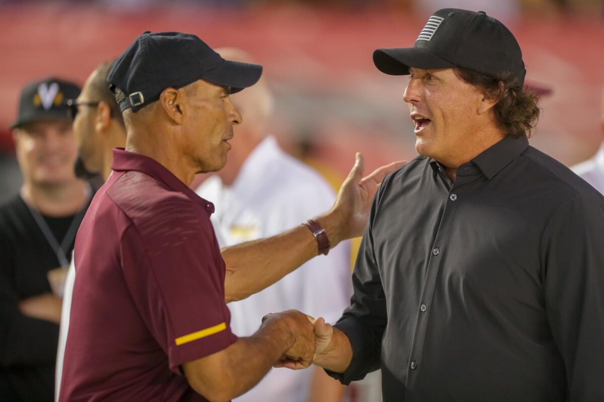 Phil Mickelson, who played for Arizona State's golf team, greets coach Herm Edwards before a game against San Diego State on Sept. 15.
