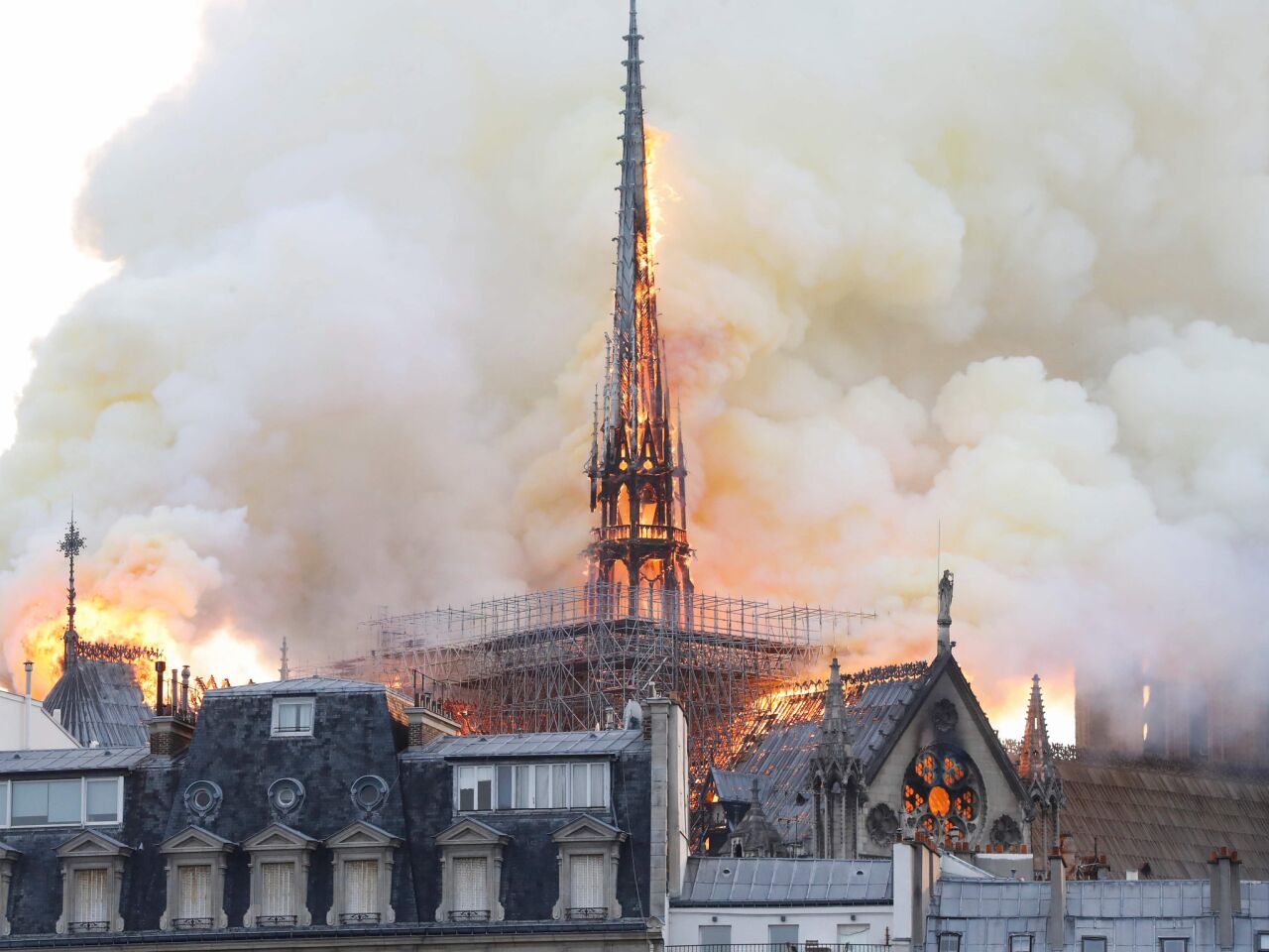 The roof at the back of Notre Dame Cathedral, behind the nave, is in flames.