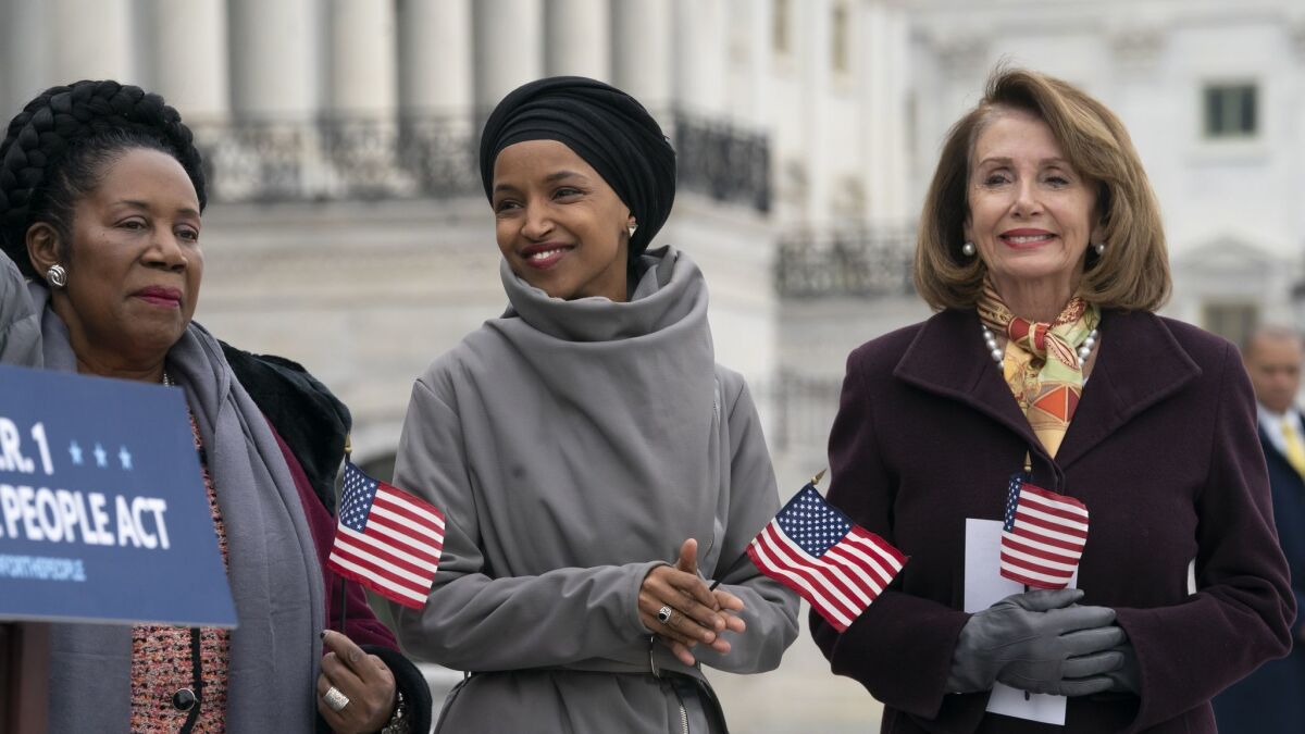 Freshman Rep. Ilhan Omar (D-Minn.), center, smiles as she stands between Rep. Sheila Jackson Lee (D-Texas), left, and Speaker of the House Nancy Pelosi (D-San Francisco), as Democrats rally outside the Capitol on March 8.