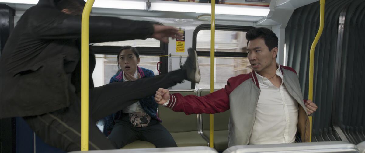 A woman seated in a subway car looks on as two men trade blows in front of her 