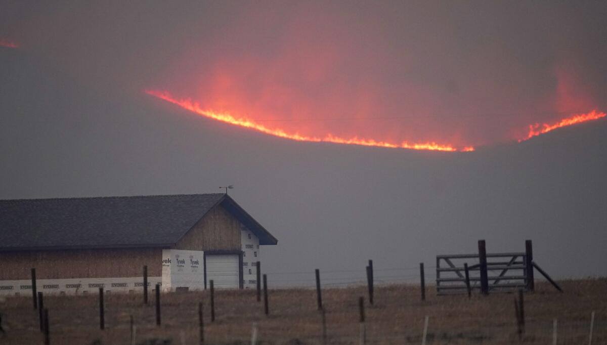 Flames on a mountain ridge ring a farm near Granby, Colo., in October 2020.