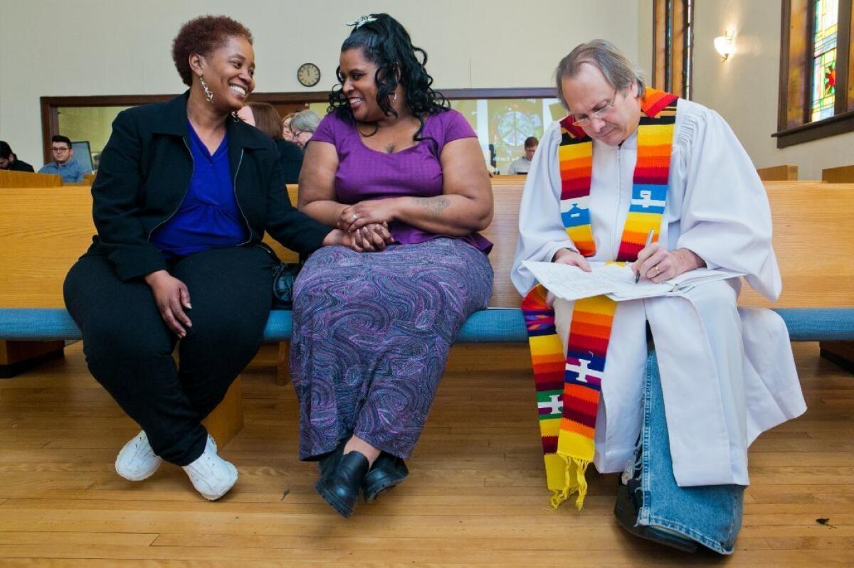 Renecia Hall, left, and Kristen Martin wait for their marriage license from Rev. Bill Freeman at Harbor Unitarian Universalist church in Muskegon, Mich., in March.