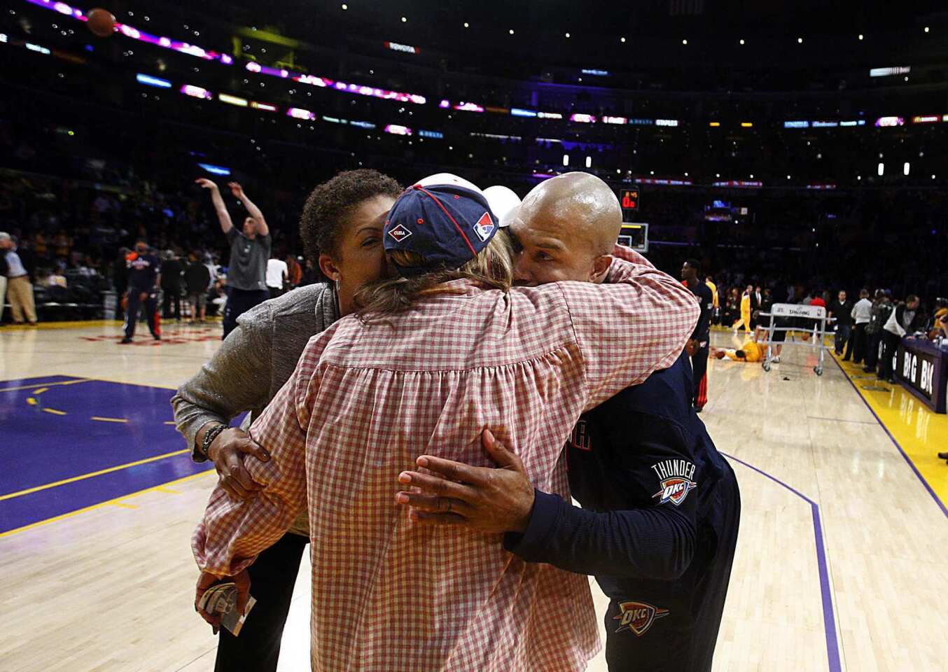 Former Lakers point guard Derek Fisher embraces TV analyst Cheryl Miller and producer/actor Penny Marshall in a group hug before playing with the Thunder against L.A. on Thursday night at Staples Center.