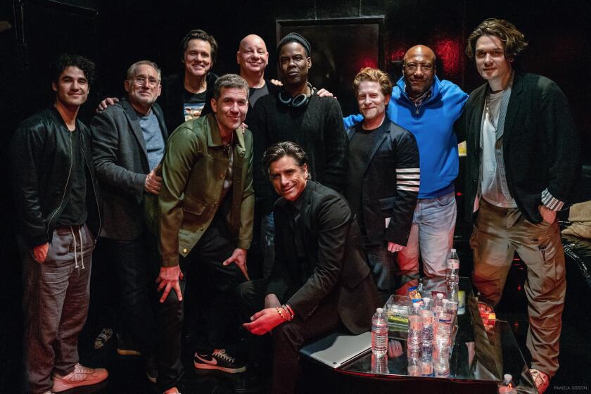 A group of 10 men pose for a photo at a comedy club