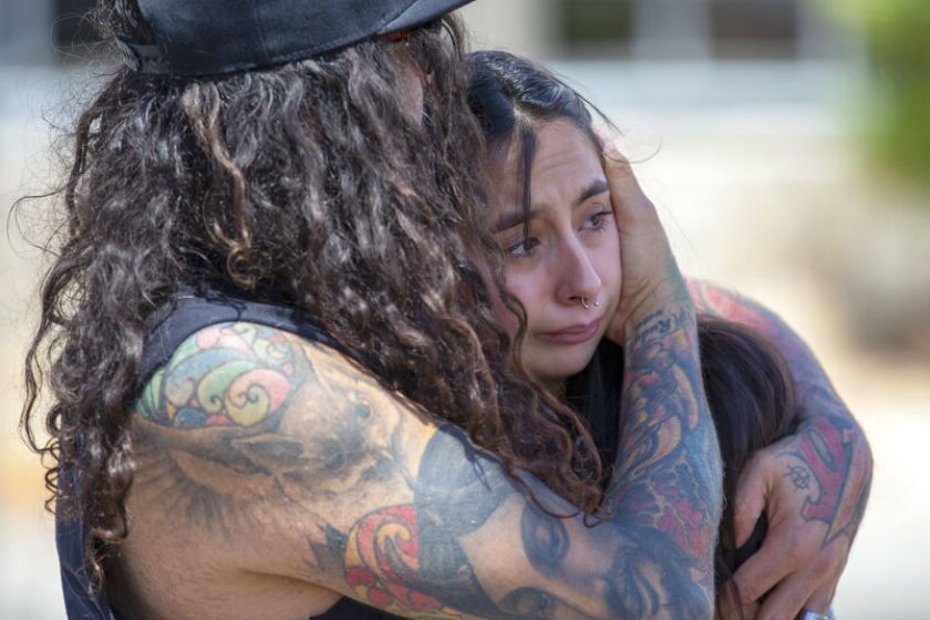 A couple embrace at the makeshift memorial for the victims of Saturday's mass shooting at a shopping complex in El Paso.