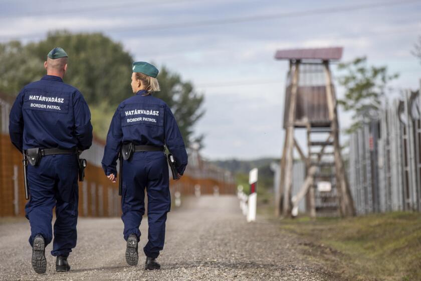 Border patrollers walk along the service route of Hungary's border with Serbia near Roszke, Southern Hungary, Wednesday, Sept. 28, 2022. Earlier this month, the first five hundred trained-up recruits were commissioned to serve in the country's newly formed border patrol unit. Their main task is to secure the state borders from trespassing by illegal immigrants. The four-meter tall wire fence was constructed in 2015 on the border sections common with Serbia and Croatia to restrict asylum-seekers to enter Hungary through official checkpoints in accordance with international and European law. (Tibor Rosta/MTI via AP)