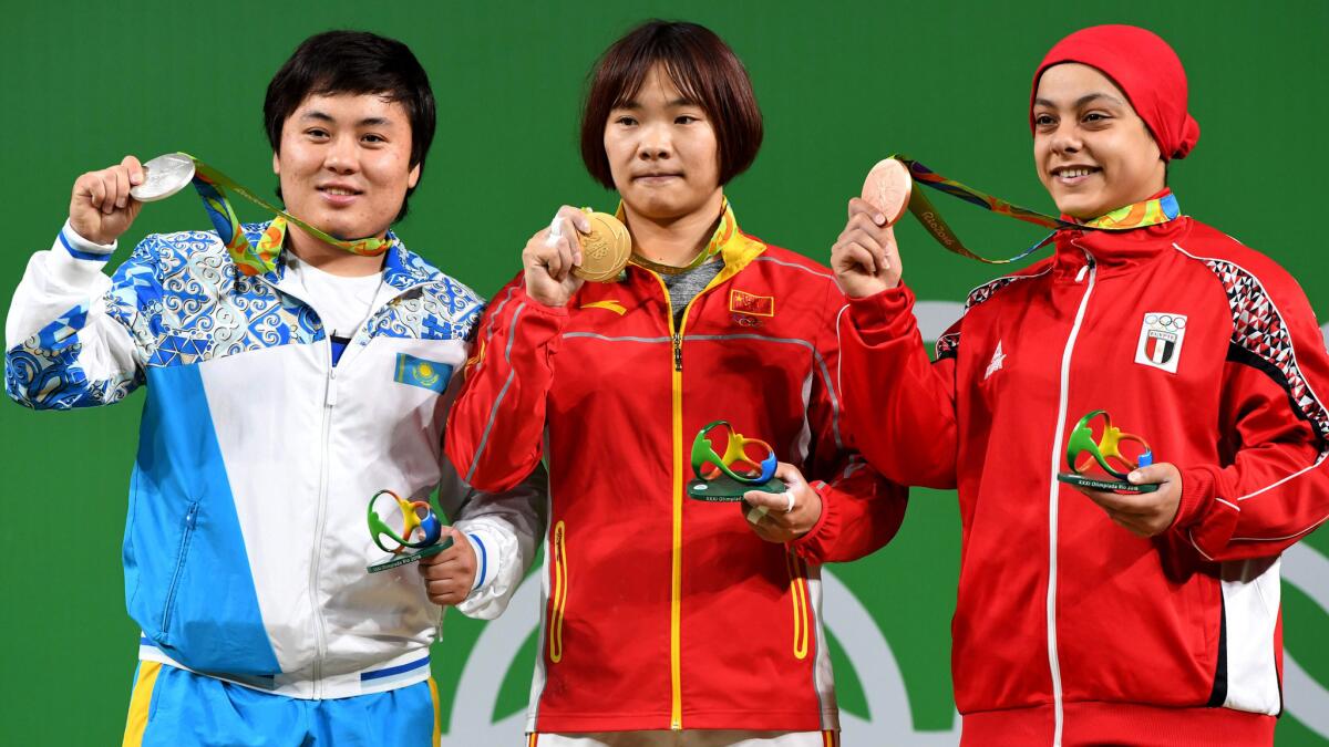 China's Xiang Yanmei, center, poses on the podium with silver medalist Zhazira Zhapparkul of Kazakhstan, left, and bronze medalist Sara Ahmed of Egypt during the awards ceremony for the women's 69-kilogram weightlifting competition.