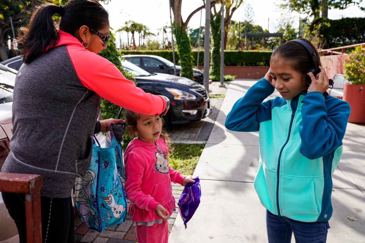 Gaby Regalado puts headphones on Jaqui Regalado, and Yuliana Regalado tries on hers at Mar Vista Family Center in April