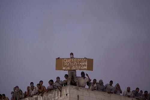Inmates gather on the roof of a building and hold up a sign that reads in Spanish, "We want better treatment by the authorities."