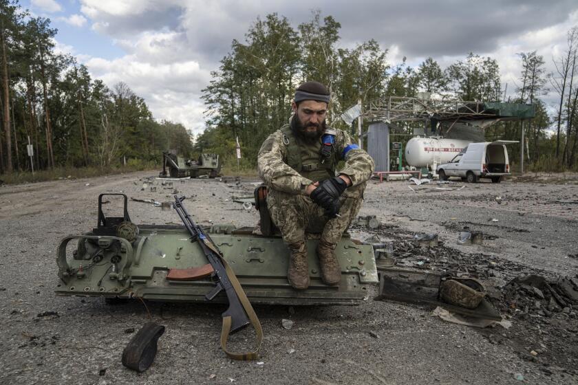 A Ukrainian serviceman smokes a cigarette after he finds and identifies a dead body of a comrade in recently recaptured town of Lyman, Ukraine, Monday, Oct. 3, 2022. (AP Photo/Evgeniy Maloletka)