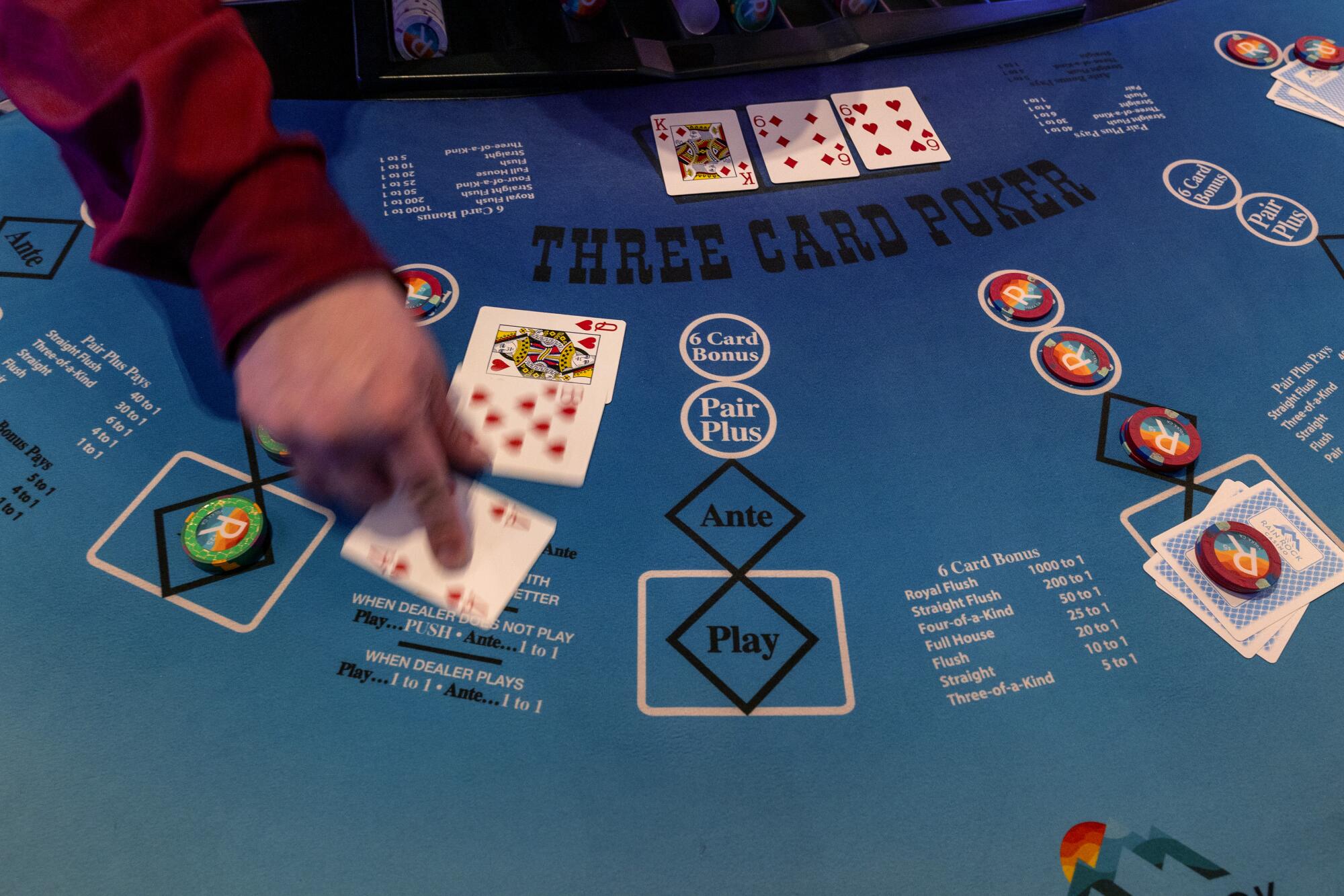 A close-up view of a dealer's hand on a poker table  