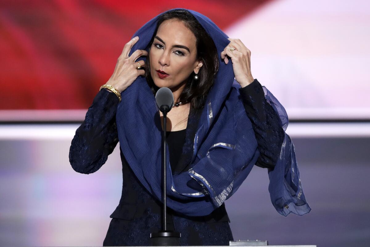 Harmeet Dhillon adjusts her headscarf as she speaks into a microphone