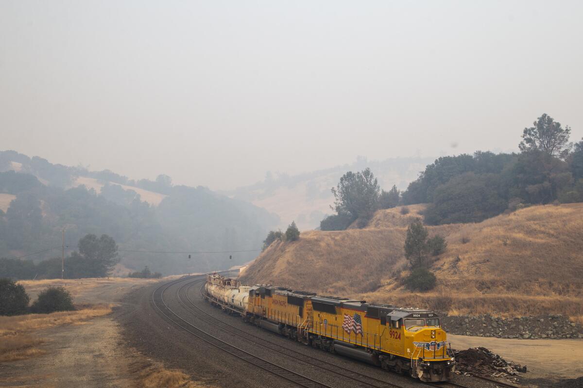 The valley behind it blanketed in a thick layer of smoke, a train sits stopped near Butte Valley along Highway 70.
