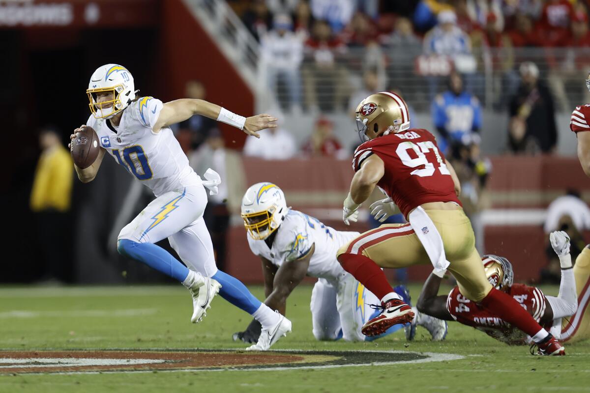 Chargers quarterback Justin Herbert runs away from 49ers defensive end Nick Bosa on Nov. 13, 2022.