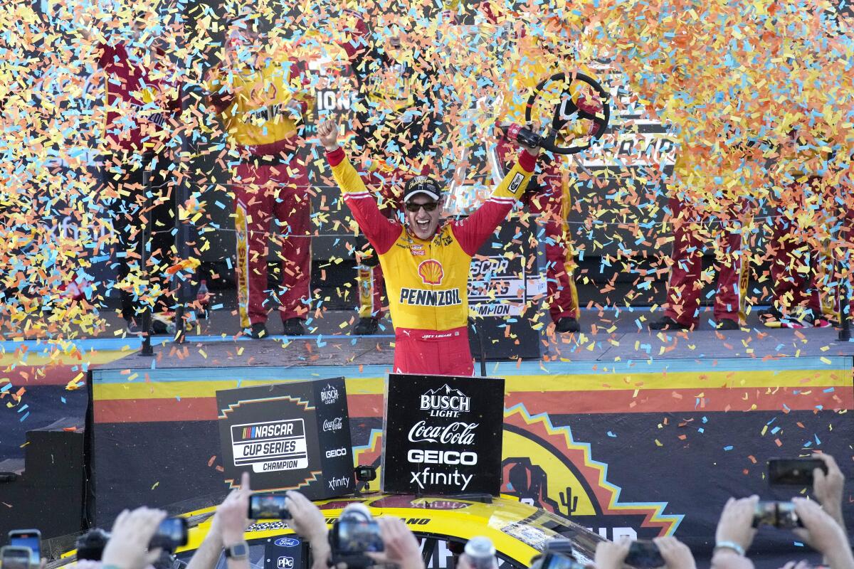 Joey Logano celebrates after winning a NASCAR Cup Series auto race and championship.
