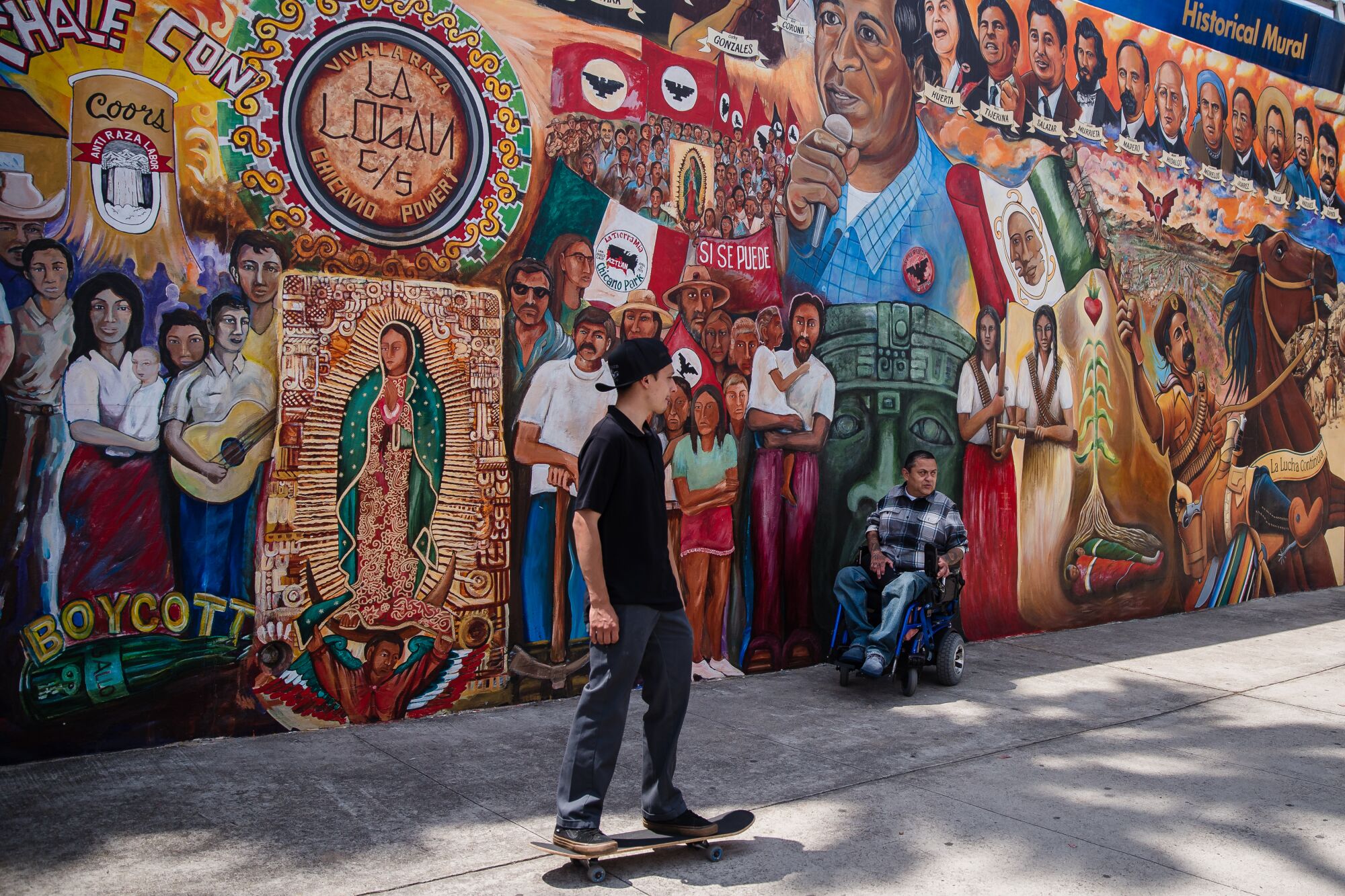 A skateboarder passes a mural at Chicano Park in Barrio Logan on April 24, 2021.