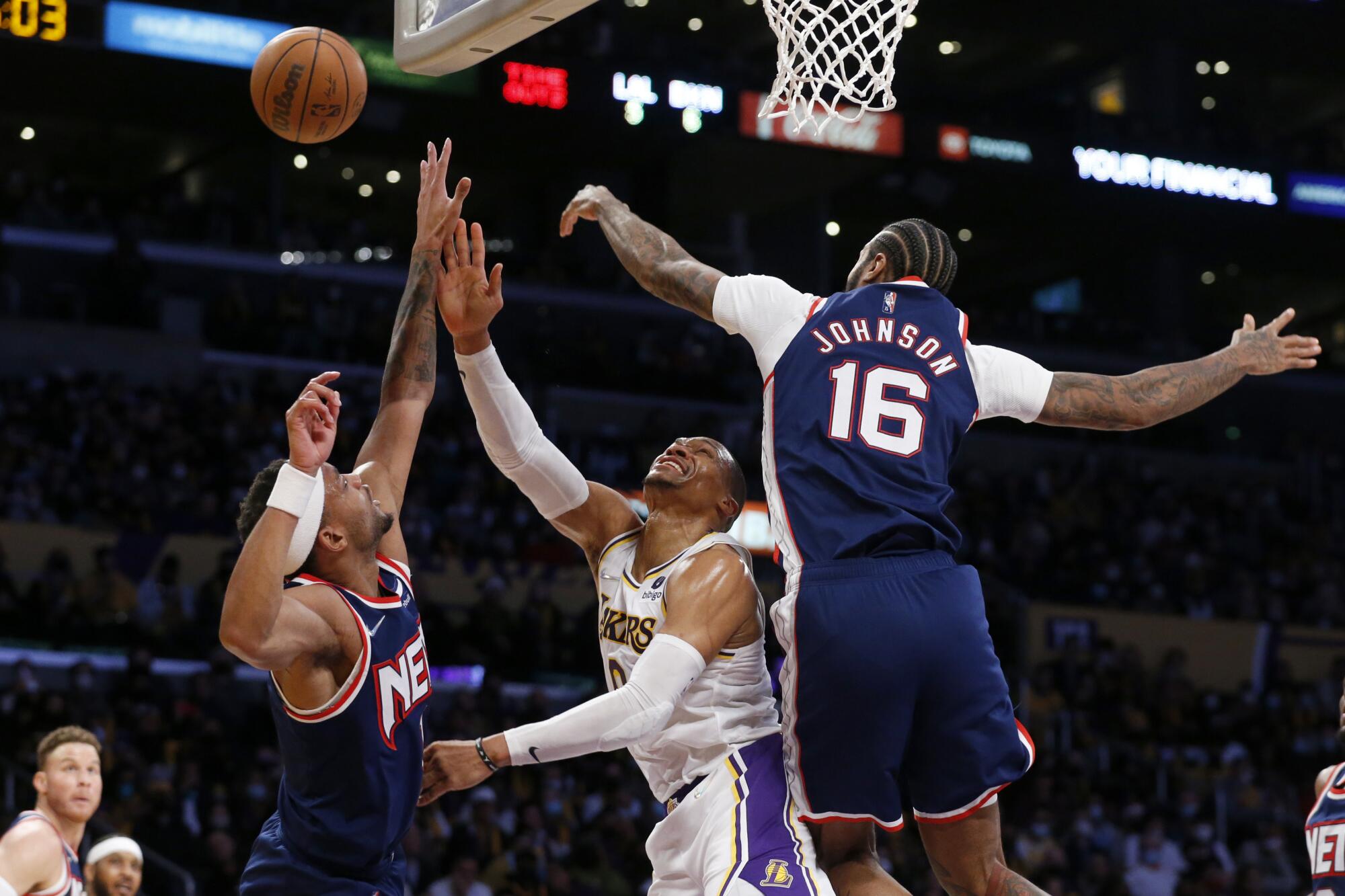 Lakers guard Russell Westbrook is fouled as he drives to the basket between two Brooklyn Nets players.