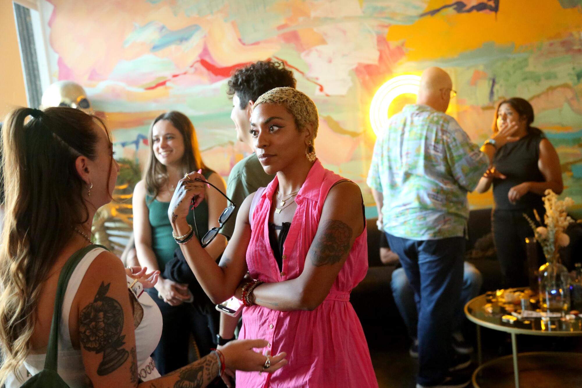 Two women chat at an event, with other people in the background.