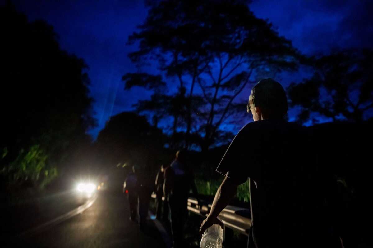 Leonardo Pereira, de 13 años y su padre, Edgar Blanco, de 46, caminan en la oscuridad hacia un refugio para dormir, en su primera parada nocturna en Colombia en el viaje que hacen a Quito, Ecuador.