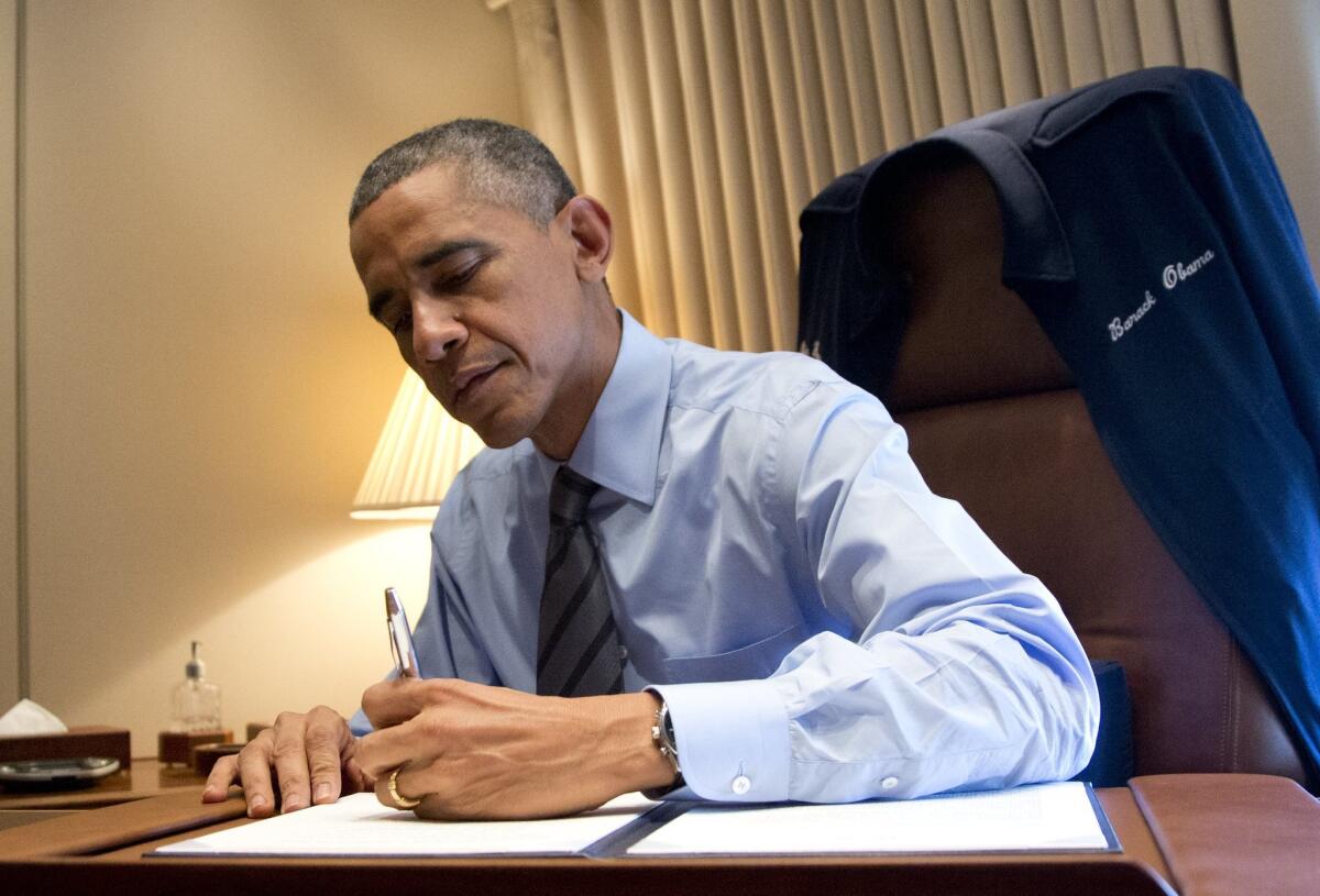 One of us? President Obama signs his executive order on immigration last month. Note how he's holding the pen.