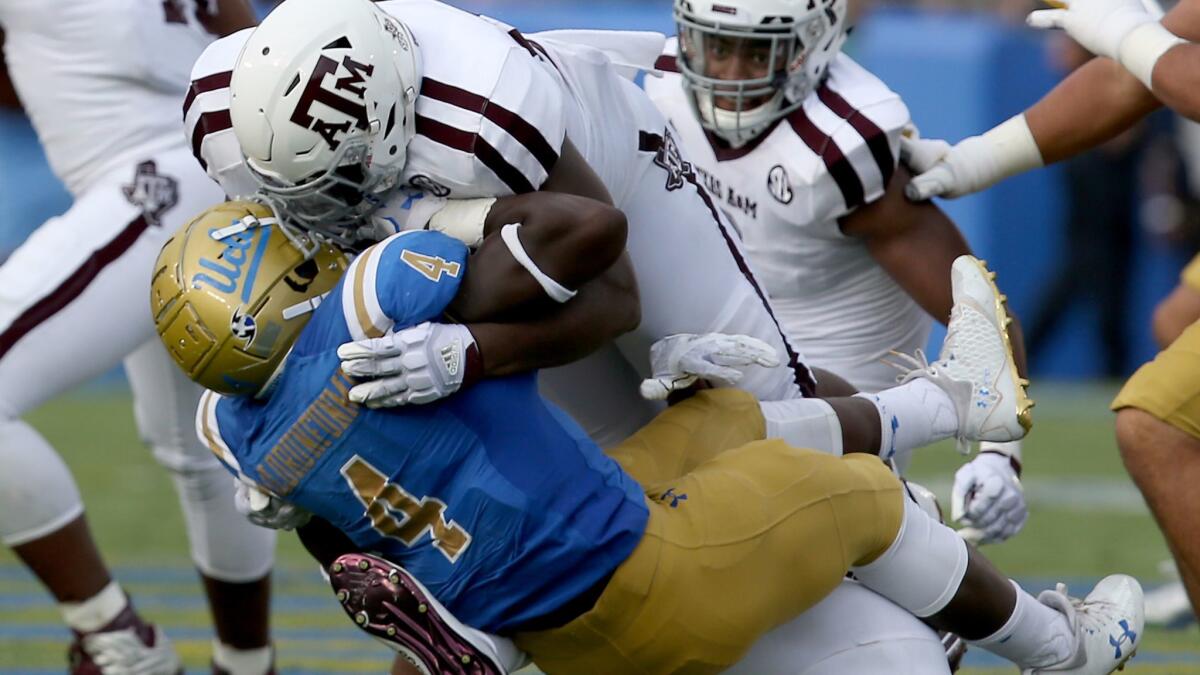 UCLA running back Bolu Olurunfunmi is brought down by Texas A&M defensive tackle Zaycoven Henderson in the first quarter Sept. 3 at the Rose Bowl.