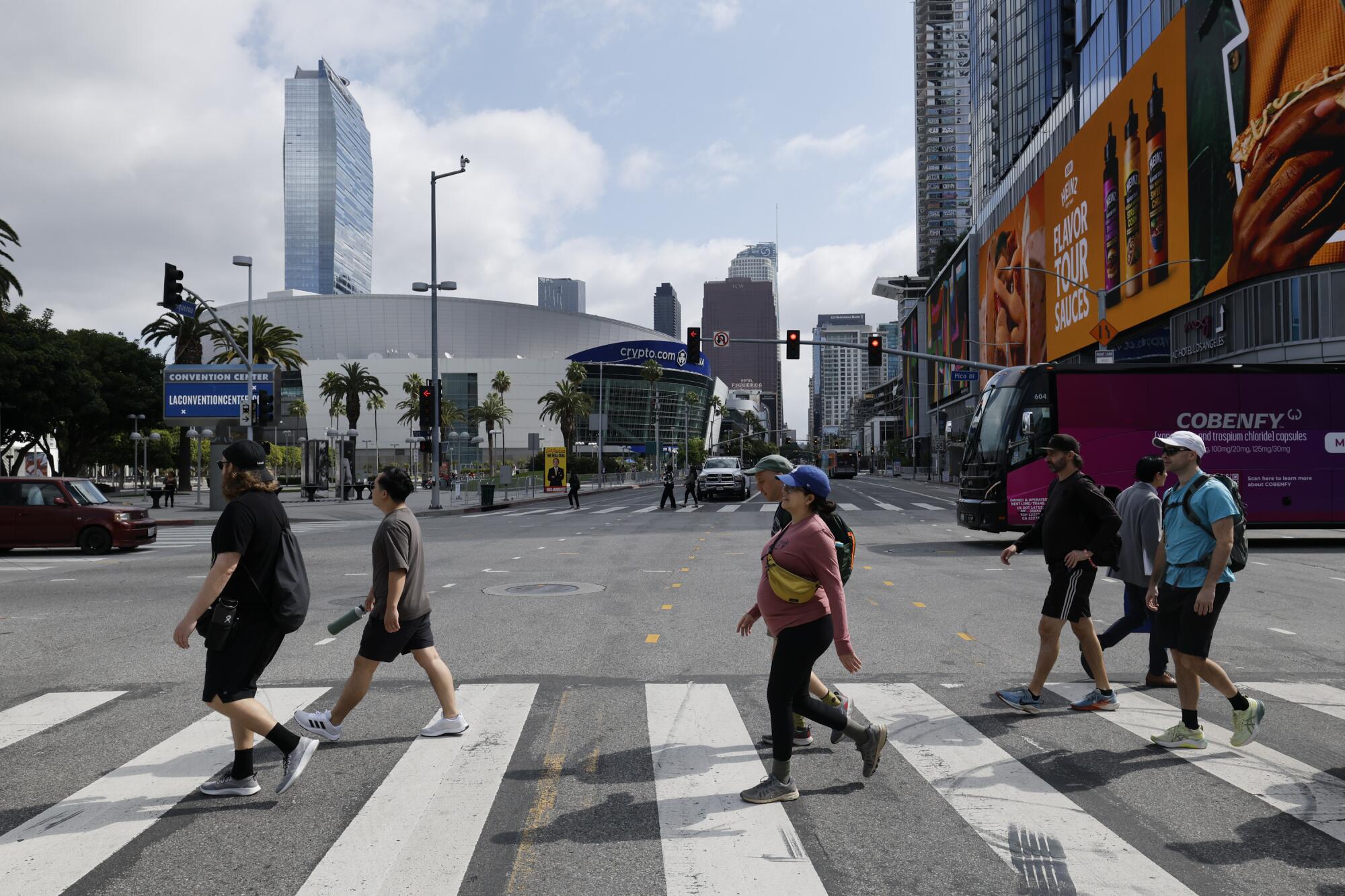Six walkers cross Figueroa Street with Crypto.com Arena in the background.