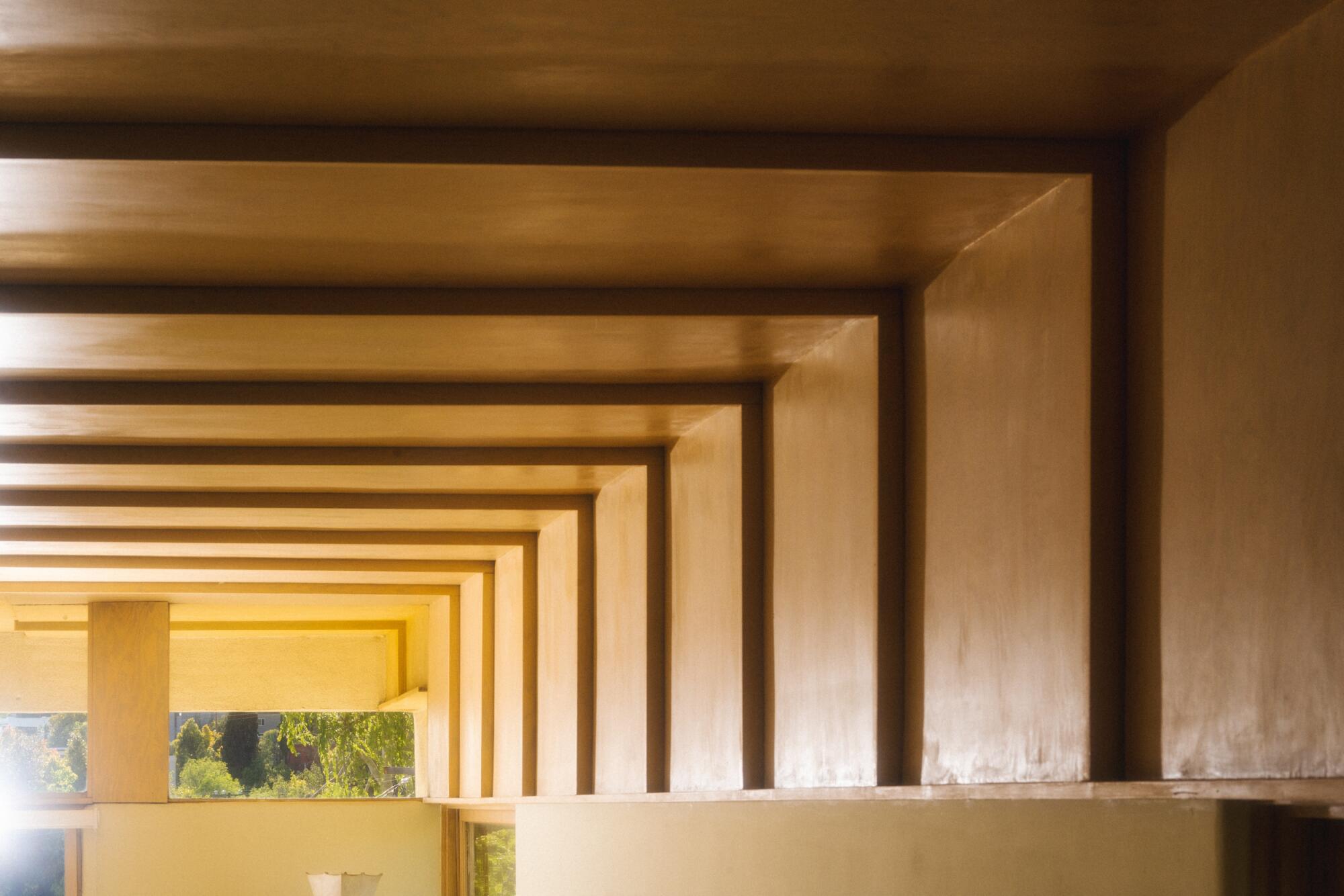 A detail of a warm wooden ceiling that recedes in concentric squares.