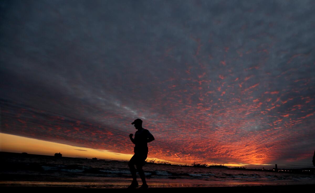 The setting sun paints the clouds coming ashore in Long Beach ahead of a powerful storm.