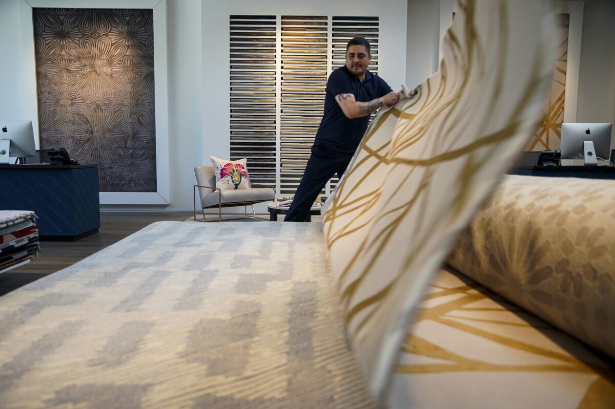 Rug Co. showroom operations manager Javier Garcia, 40,  displays sample rugs during a recent visit.