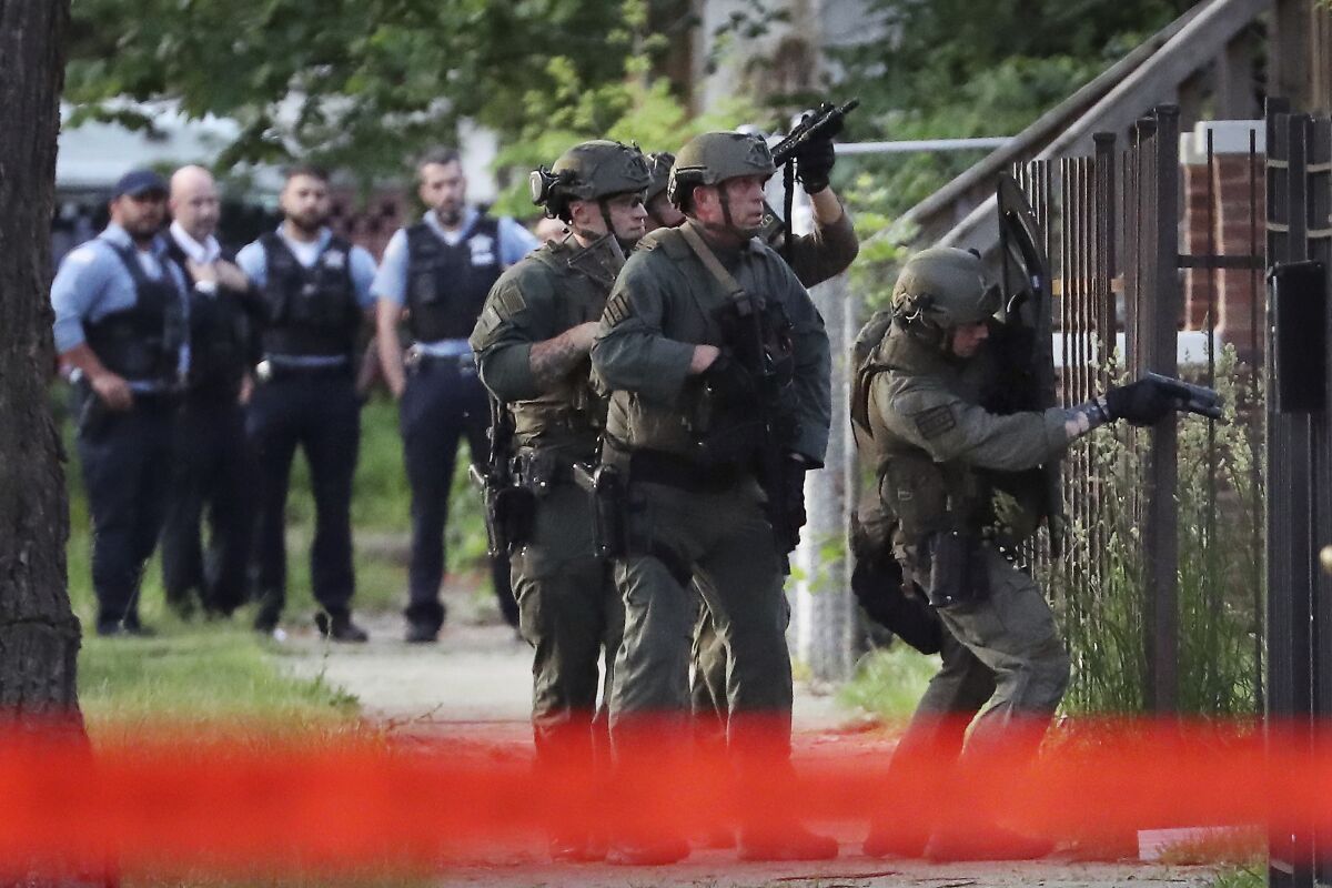 Law enforcement personnel search a property on the 6300 block of S. Bishop Street in Chicago, Wednesday, June 1, 2022, after a Chicago police officer was shot and wounded nearby. (Terrence Antonio James/Chicago Tribune via AP)
